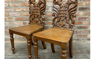 A pair of Victorian oak hall chairs with carved twin eagle b...