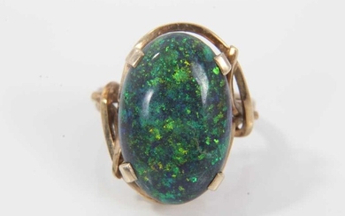 Black opal single stone ring with an oval black opal cabochon measuring approximately 20mm x 13mm x 4.2mm in a 9ct gold setting. Ring size O.