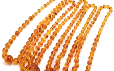 FIVE POLYBERN AMBER GRADUATED BEAD NECKLACES; 1.2-3cm near round beads, lengths 73 & 77cm.