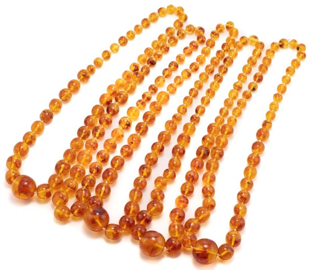 FIVE POLYBERN AMBER GRADUATED BEAD NECKLACES; 1.2-3cm near round beads, lengths 73 & 77cm.