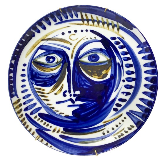 Porcelain wall plate depicting face in blue shades. In...
