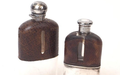 Two Victorian silver and leather mounted glass hip flasks, the larger example London, c.1889, the smaller example London, c.1873, both with maker's marks rubbed, the larger flask with bayonet cap and drinking cup deficient, the smaller with screw...