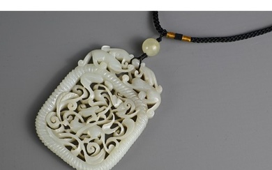 A CHINESE PALE CELADON JADE PENDANT. Carved and pierced feat...