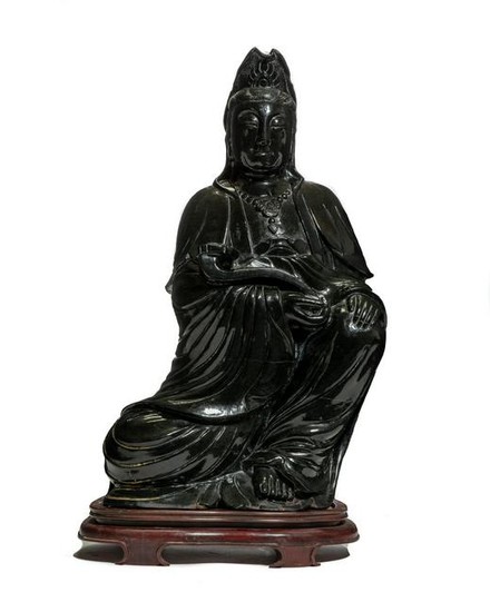 A Chinese serpentine figure of seated Guanyin