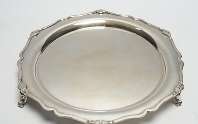 A George V silver shaped circular salver, on three scroll fe...