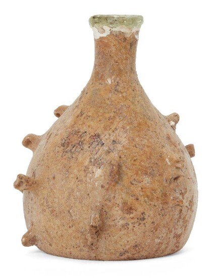 A Roman bottle with pinched projections, Eastern Mediterranean, circa 5th-6th century AD., the free-blown rounded body tapering to a short cylindrical neck. The body is decorated with a series of pinched projections, the base indented, the surface...