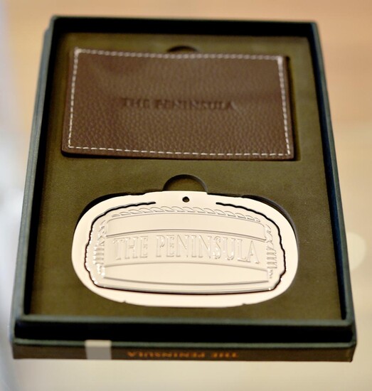 A SILVER PLATED PAGE BOY HAT BOOKMARK FROM THE PENINSULA HOTEL HONG KONG, WITH LEATHER POUCH, BOXED.