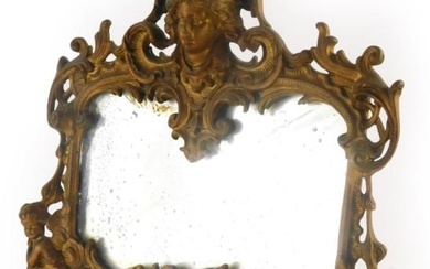 A gilt metal mirror, the frame decorated with masks,...