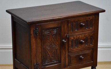 A reproduction oak side cabinet with carved panelled door flanked...