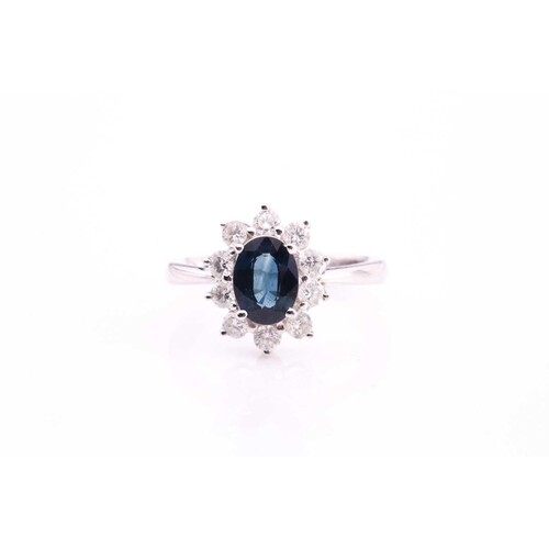 A sapphire and diamond cluster ring, set with an oval sapphi...