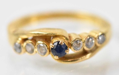 A yellow metal ring set with central blue stone flanked...