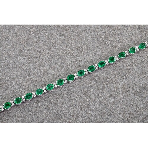 An 18ct white gold, emerald and diamond bracelet, the oval c...