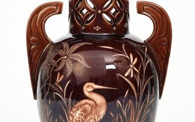 An Aesthetic Movement Wedgwood Vigornian vase, shouldered form with winged handles, the cylindrical neck with pierced design, the body acid etched with a crane wading in a wild pond, dragonflies resting on the reeds, covered in a brown glaze, unsigned...