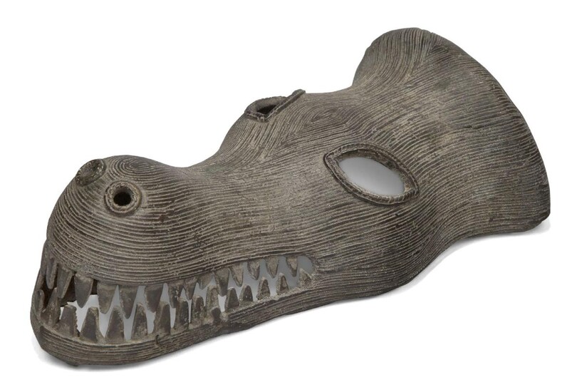 An African bronze crocodile mask, probably West African, 20th century, modelled as a crocodile head baring teeth, with all over incised linear decoration, 27cm long