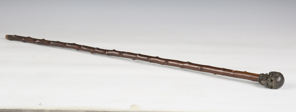 An early 20th century walking cane, the cast metal handle modelled in the form of a skull, length 87