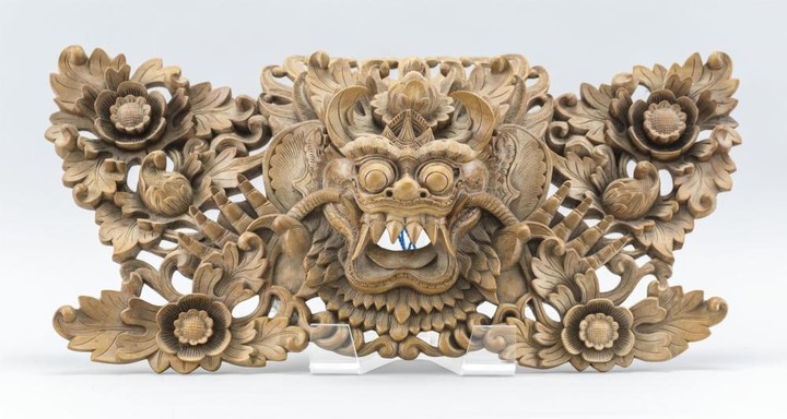 CHINESE CARVED TEAKWOOD FIGURAL WALL HANGING Head of an open-mouthed fanged mythological beast at center, surrounded by openwork flo...