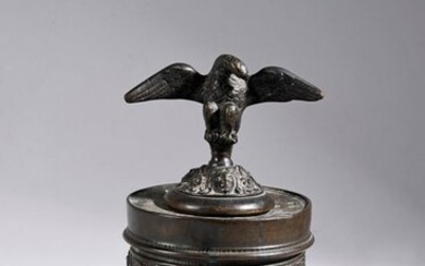 Cast and chiselled bronze inkwell, the round body with friezes of foliated scrolls and grimacing masks rests on three stylized lions, the lid topped by an eagle with outstretched wings.