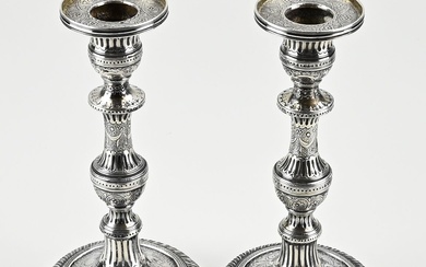 Deux chandeliers anciens en argent, sur un pied rond à décor torsadé. Les piliers contournés,...