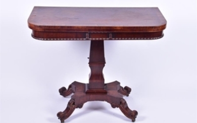 A 19th century rosewood fold over card table in the Regency style, with shaped column on a quatrefoil base, terminating...