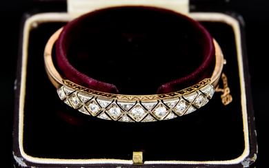 A Diamond Stiff Bracelet, Early 20th Century, in gold coloured...