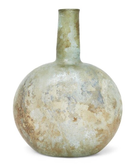A Roman green glass vessel of spherical form the sides slightly flattened, with cylindrical neck and thickened in-turned uneven rim, a series of wheel-cut bands around the base of the neck, circa 3rd Century A.D., 23cm high Provenance: Acquired by...