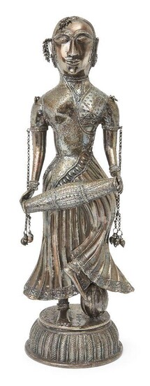 A large silvered metal figure of a female drummer, India, 20th century, on a high domed base, her robes with pattered detail and chain attachments to arms, ear and forehead, 47.3cm. high