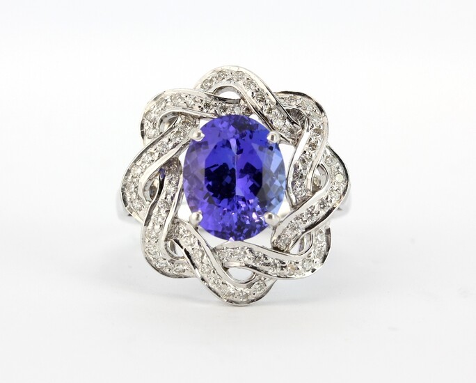 A lovely 14ct white gold ring set with a large oval cut tanzanite surrounded by brilliant cut diamonds, (O.5).
