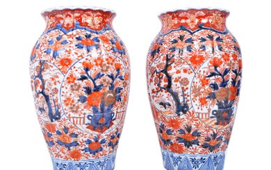 A pair of late nineteenth century Japanese Imari urns, featuring blue and red floral motifs and patterns, with a central bouquet / tree display. Some light damage & restoration noticeable to the rims. Unmarked to base. Measures approx. 33cm tall.