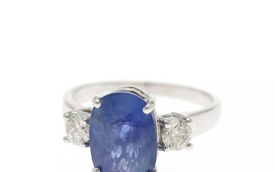 A sapphire and diamond ring set with an oval-cut sapphire flanked by two diamonds, mounted in 14k white gold. Size 52.