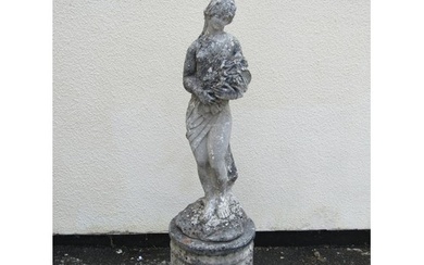 A weathered cast composition stone garden figure of a standi...