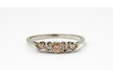 A white gold ring set with central brown diamond flanked by ...