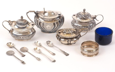 Four silver mustards, together with five various silver condiment spoons and a silver napkin ring, the mustards including a repousse decorated oval example, Birmingham, c.1908, S Glass and a fluted, monogrammed example, Sheffield, c.1891, Atkin...