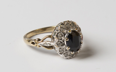 A 9ct gold, sapphire and diamond oval cluster ring, claw set with the oval cut sapphire within a sur