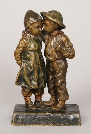 A COLD PAINTED BRONZE GROUP FIGURE OF A BOY WHISPERING TO A GIRL
