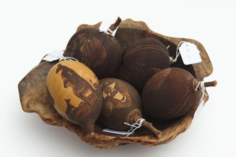 A COLLECTION OF FIVE CARVED BAOBAB NUTS WITH INCISED DECORATION BY ARTISTS INCLUDING JIMMY J, BOBBIE DAZZLER AND JABBI, TOGETHER WIT...
