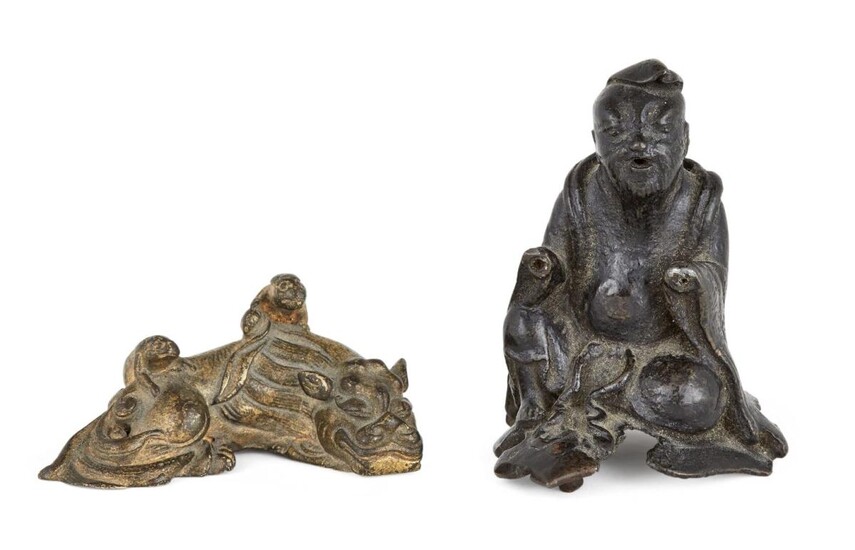 A Chinese Ming-style gilt bronze scroll weight and a bronze finial, Ming and early 20th dynasty, the weight cast as a recumbent lion with two small temple lions climbing atop its back, the finial cast as a seated scholar, 6.5cm wide (2)
