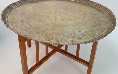 A MIDDLE EASTERN BRASS TOPPED TABLE WITH FOLDING WOODEN...