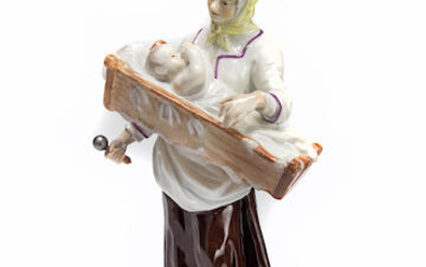 A Meissen figure of a mother holding a child in a crib