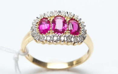 A RUBY AND DIAMOND RING IN TWO TONE 18CT GOLD, FEATURING THREE OVAL CUT RUBIES TOTALLING 1.25CTS, WITH A BORDER OF DIAMONDS TOTALLIN...