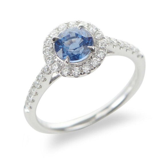 A SAPPHIRE AND DIAMOND CLUSTER RING IN 18CT WHITE GOLD, CENTRALLY SET WITH A ROUND CUT BLUE SAPPHIRE OF 1.20CTS, IN A SURROUND OF DI...