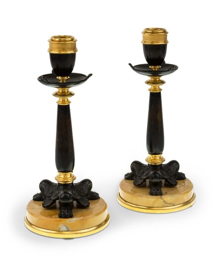 A pair of French gilt and patinated bronze candlesticks, late 19th century, each with urn sconce on column support and tri-from base with lion paw feet, on circular marble base, 23.5cm high (2)