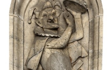 A portico shaped sandstone wall panel, decorated in relief with a fool playing the tambourine. 20th century. Total H. 137. W. 76 cm.
