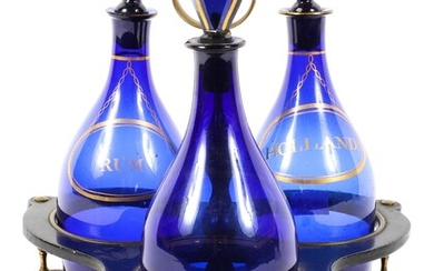 A set of three Regency Bristol blue glass spirit decanters in a papier-mache and brass stand