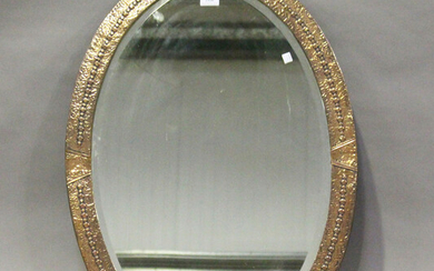 An early 20th century Arts and Crafts oval copper wall mirror with hammered decoration, 85cm x 60cm.