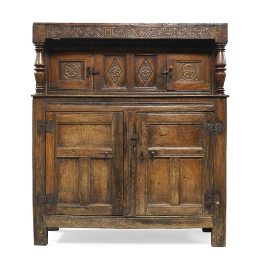 An oak Court Cupboard, 17th century and later, the top frieze carved MLA:MK:1682', above two central carved panels flanked by two carved panelled doors and turned columns supports, above two further panelled doors enclosing shelf space, 163cm high...