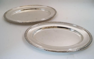 Two silver plated oval serving platters by Christofle, both with a ribbon and reed border, both marked to underside, 50.2cm wide, 35.5cm deep, and 45.9cm wide, 32.5cm deep (2)