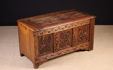 A Carved Oak Linen Chest/ Coffer. The hinged lid having a moulded edge with one end cut off, above a