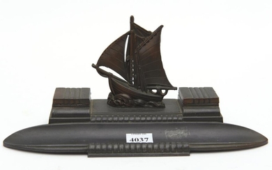 A FRENCH BRONZE DESK STAND, WITH TWO LIDDED INKWELLS AND A PEN TRAY, SURMOUNTED BY A SAILING SHIP FINIAL, 25 CM WIDE, 11 CM HIGH