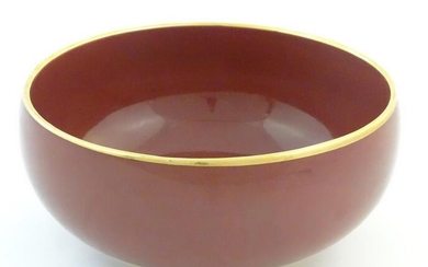 A Japanese bowl with a red glaze and gilt rim.