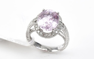 A KUNZITE AND DIAMOND COCKTAIL RING - Featuring an oval cut kunzite weighing 5.71cts, surrounded and shouldered by round brilliant c...